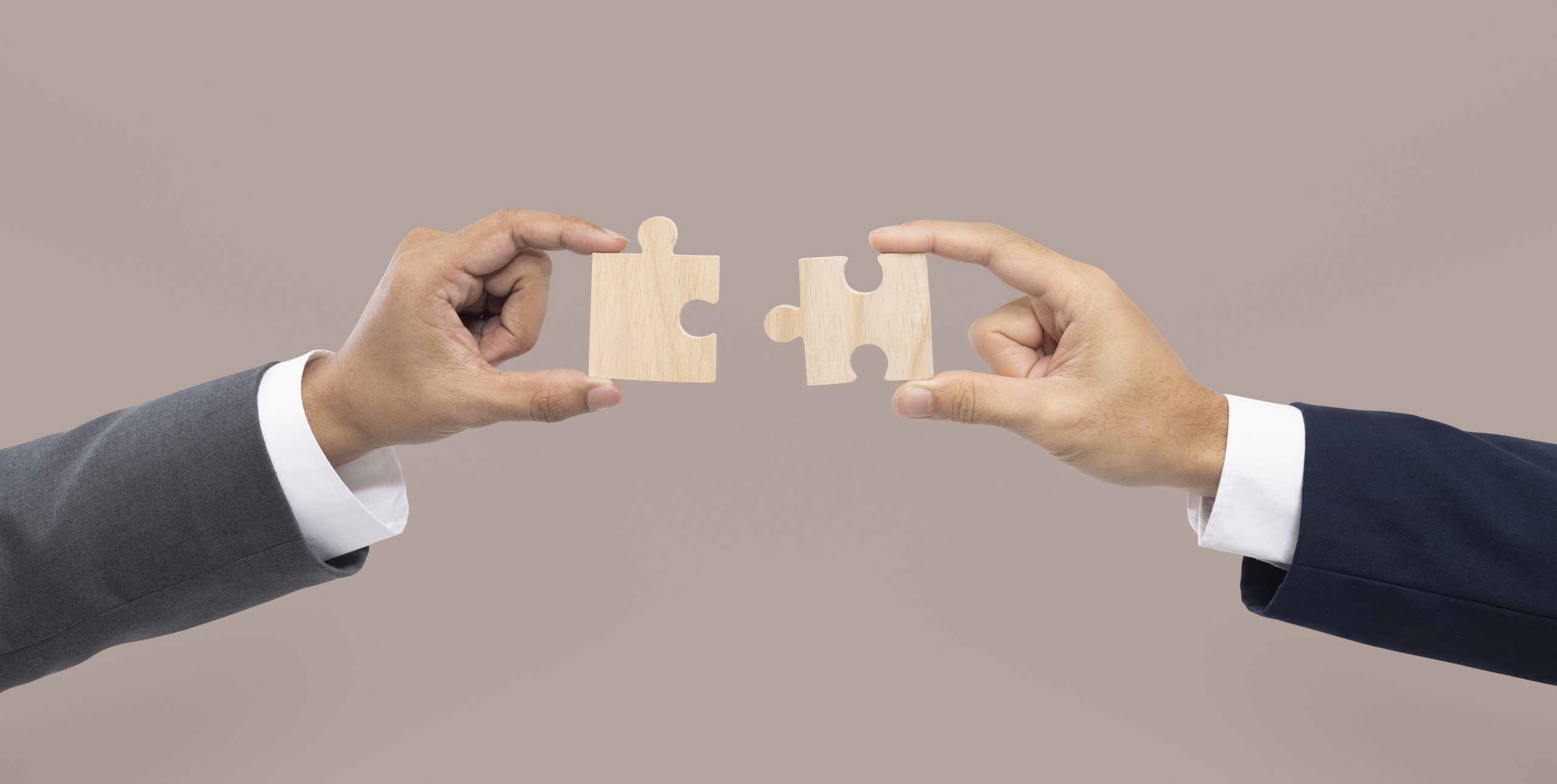 Two hands holding two puzzle pieces